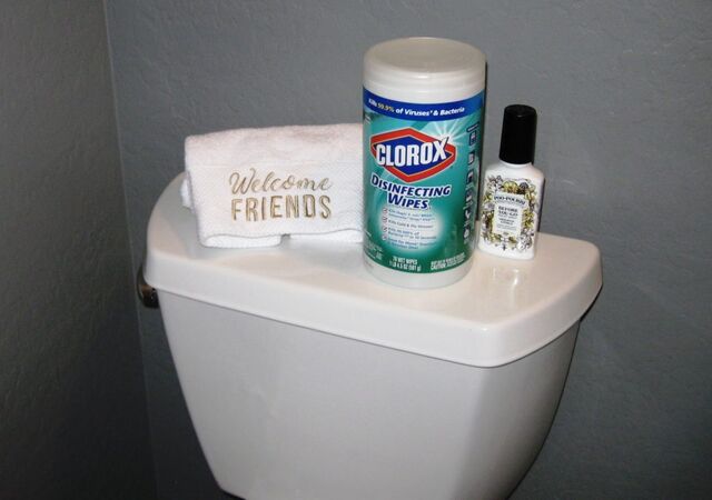 A "welcome friends" guest towel next to a cannister of Clorox wipes in the powder room.
