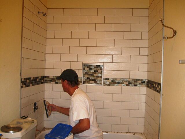 John at the grouting stage after tiling the tub surround in our guest bathroom.
