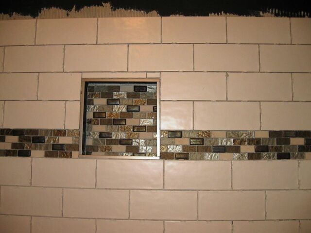 The bathtub tiling remodel is coming along with white subway tiles and beautiful glass accents.