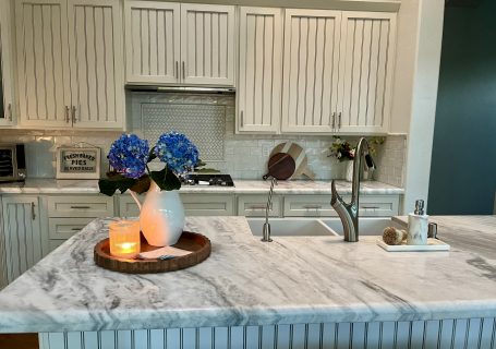 White kitchen island with blue hydrangeas, a candle and simple everyday decor