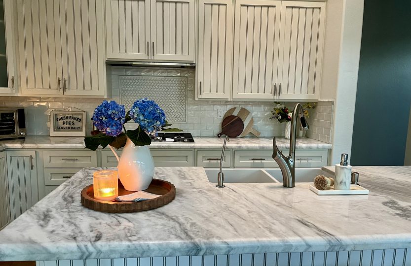 White kitchen island with blue hydrangeas, a candle and simple everyday decor