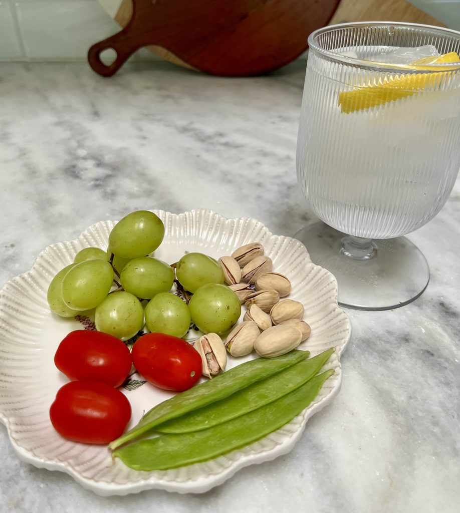 Simple crudité platter with grapes, tomatoes, snap peas and pistachios