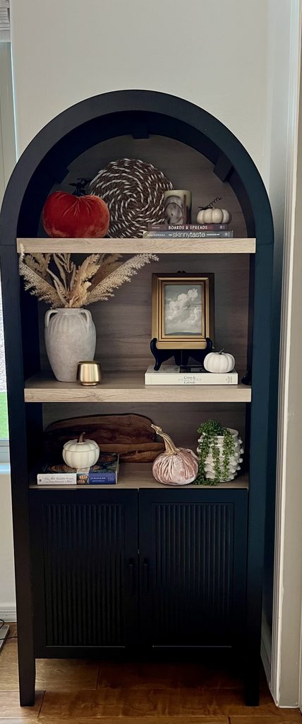 arched bookcase decorated with pumpkins, books and dried grasses for fall