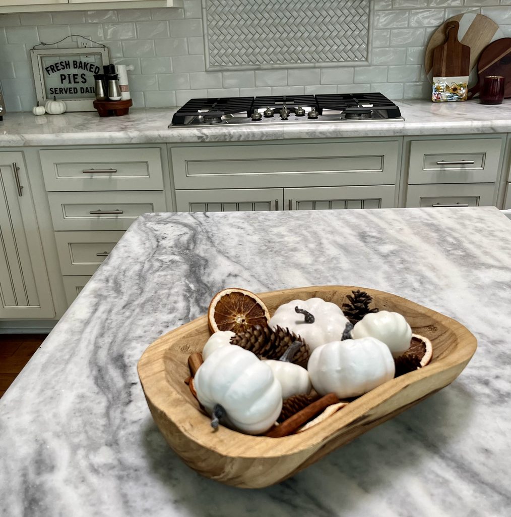 imple fall decor with white pumpkins, pinecones and dried oranges on a kitchen island