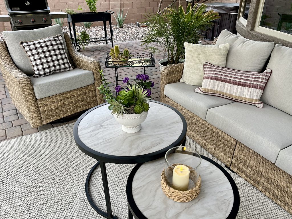 Plaid pillows and cream cushions on a neutral outdoor patio for fall