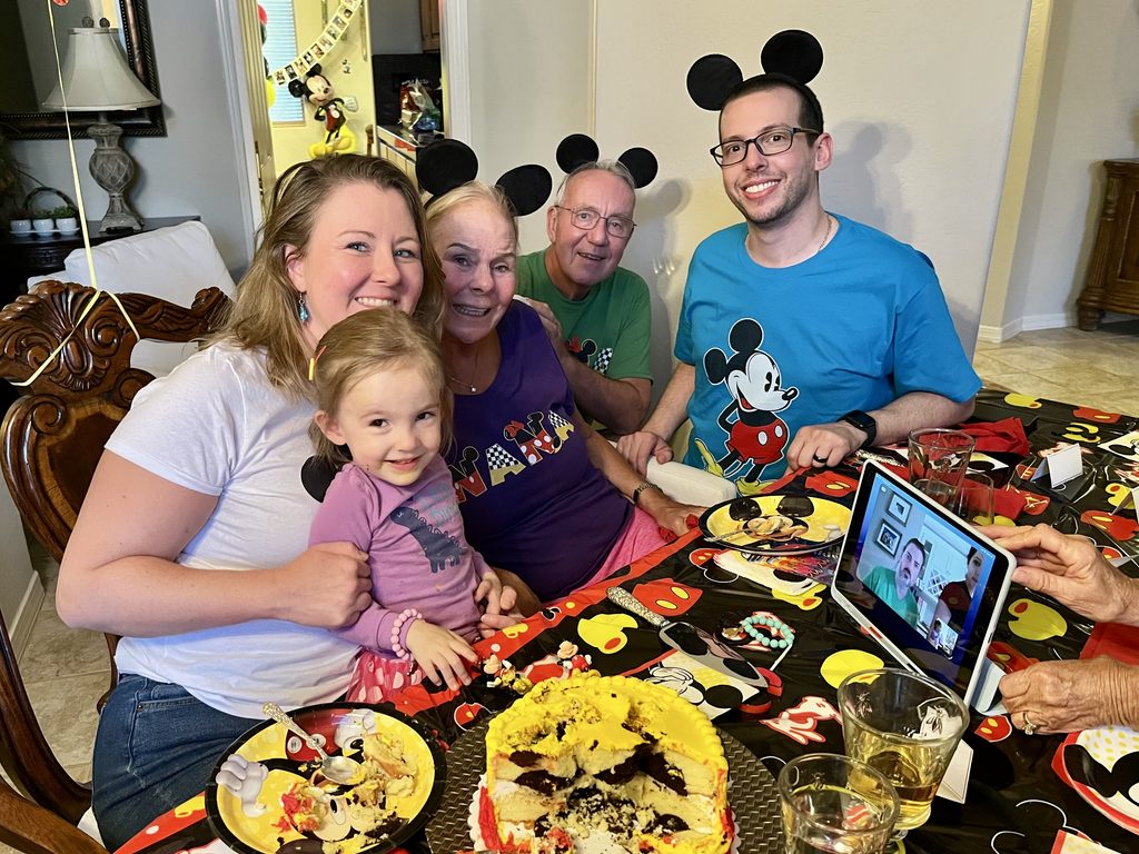 Family celebrates a three-year-old’s Mickey Mouse birthday with themed decorations and a birthday cake