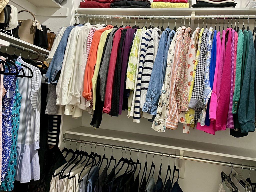 Color-organized tops and neatly hung pants in a walk-in closet