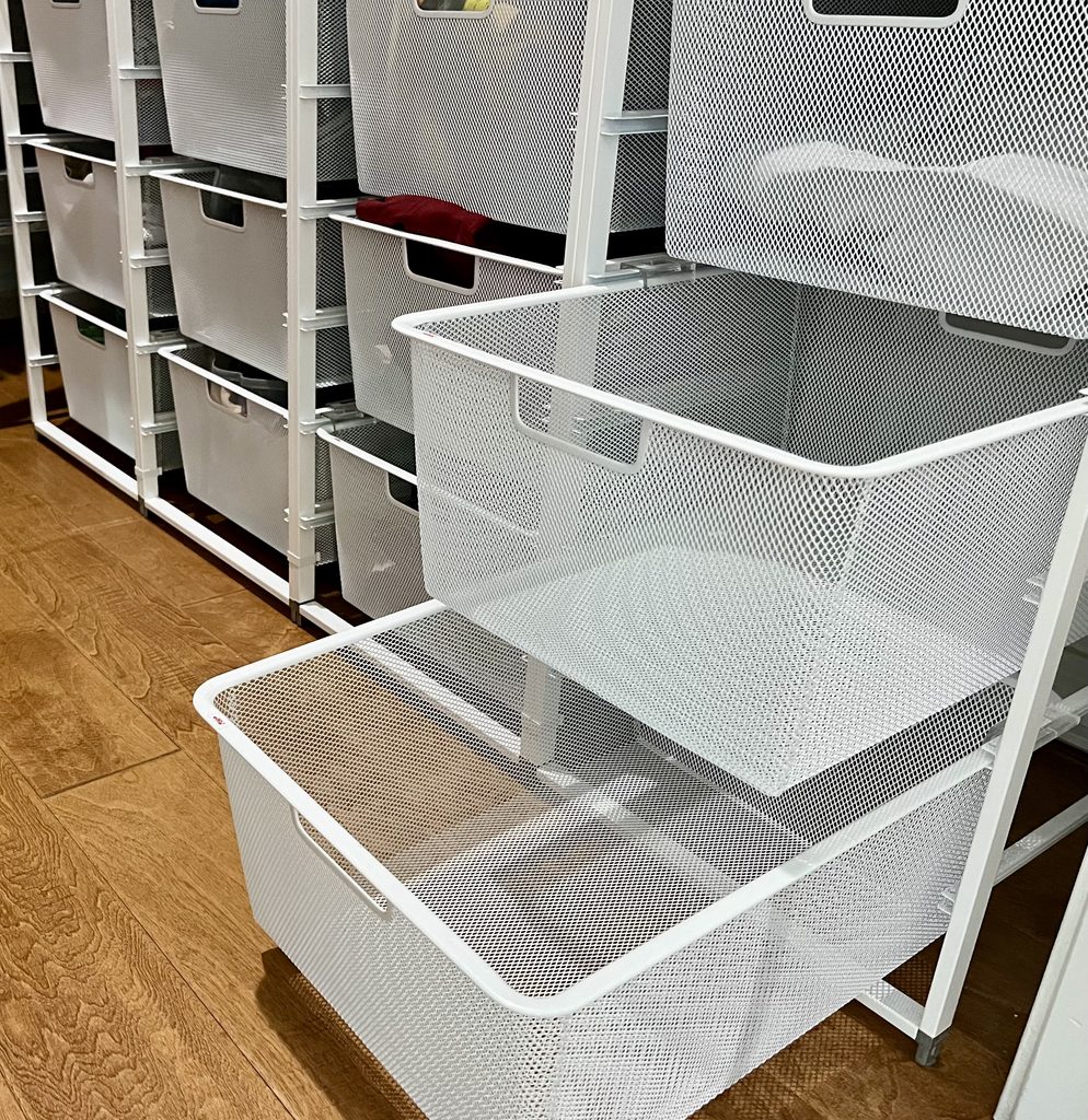 Empty white Elfa mesh drawers after decluttering and organizing a walk-in closet.