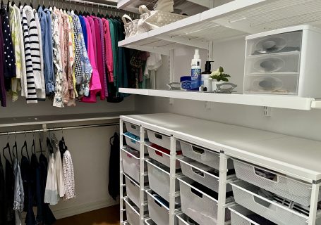 Walk-in closet with clothes arranged by color and white Elfa mesh drawers