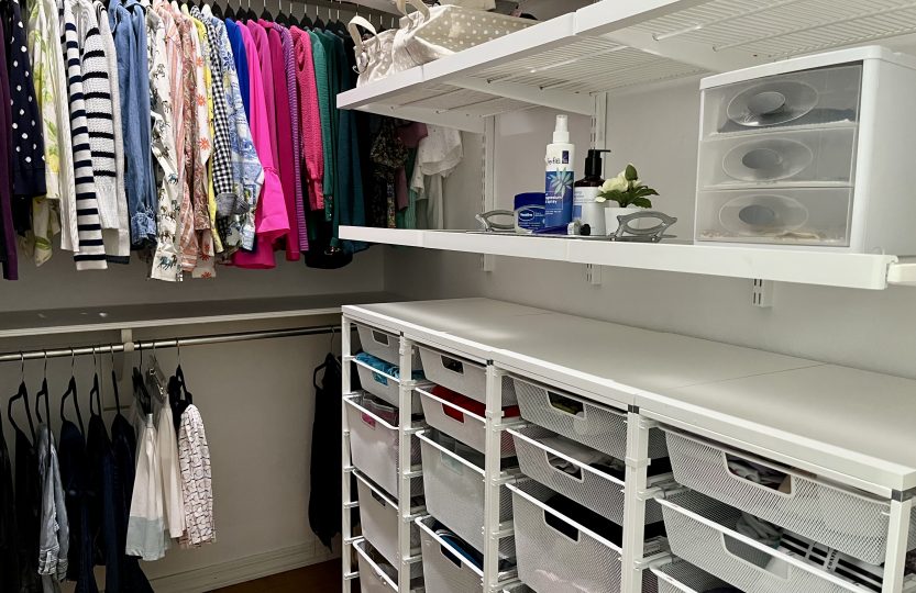Walk-in closet with clothes arranged by color and white Elfa mesh drawers