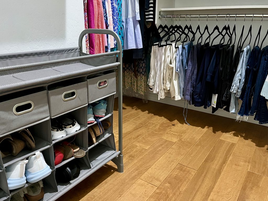 Organized shoes and neatly hung pants in organized closet.